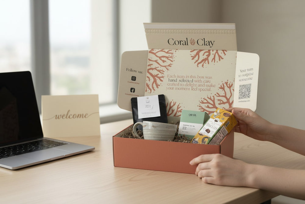 Het uitpakken van een Coral & Clay-medewerkersgiftbox op een bureau met een laptop en een ‘welcome’-kaart.