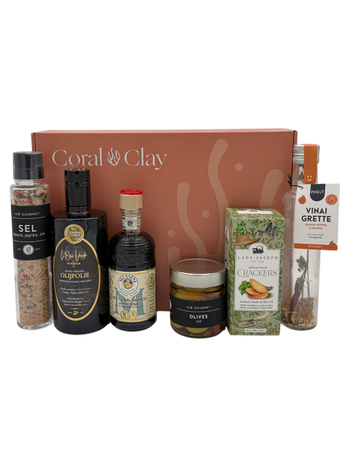 Collectie gourmetproducten, waaronder flessen, potjes en dozen met ‘Coral Clay’-logo op een witte achtergrond.