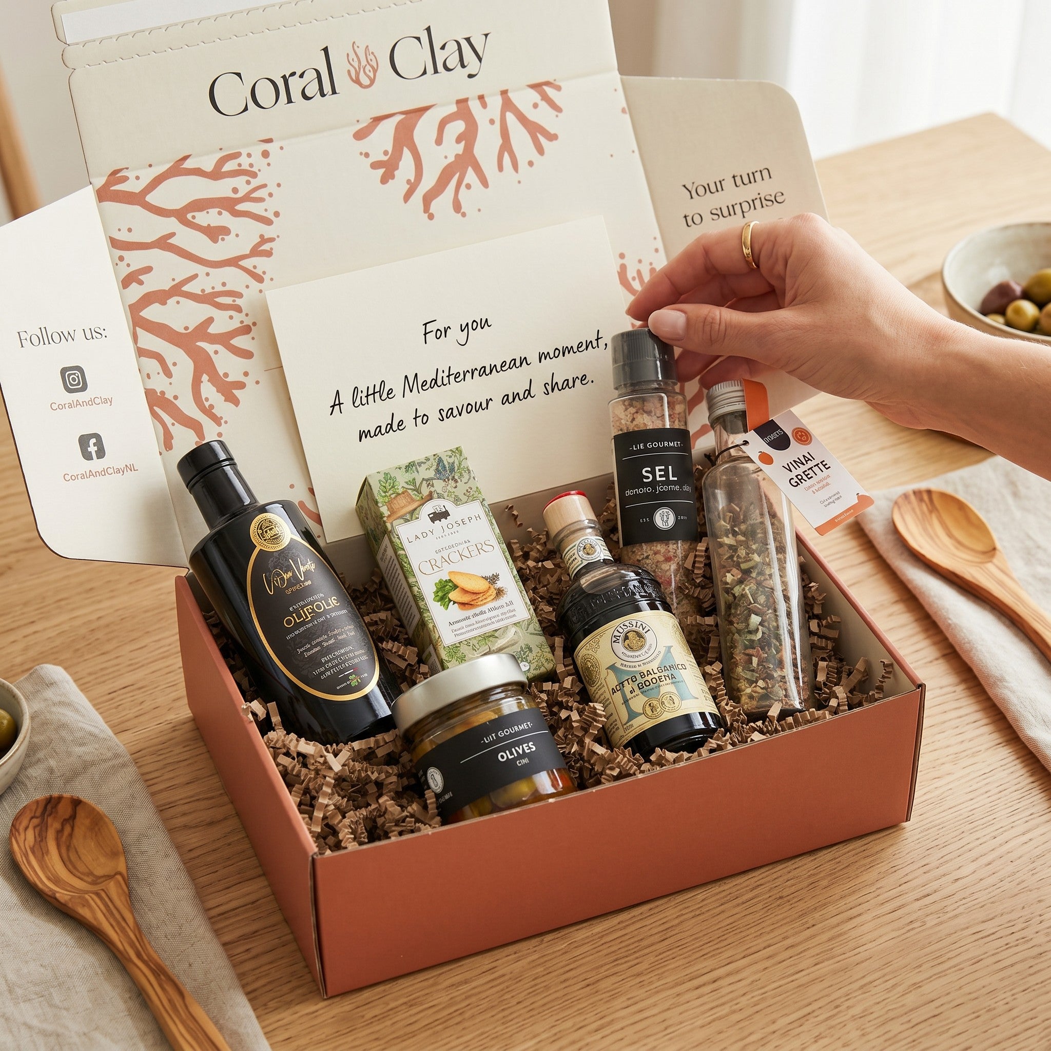 Luxury Mediterranean Signature Gift with Puglia olive oil, balsamic vinegar, olives, crackers, vinaigrette and seasoning grinder on wooden board.