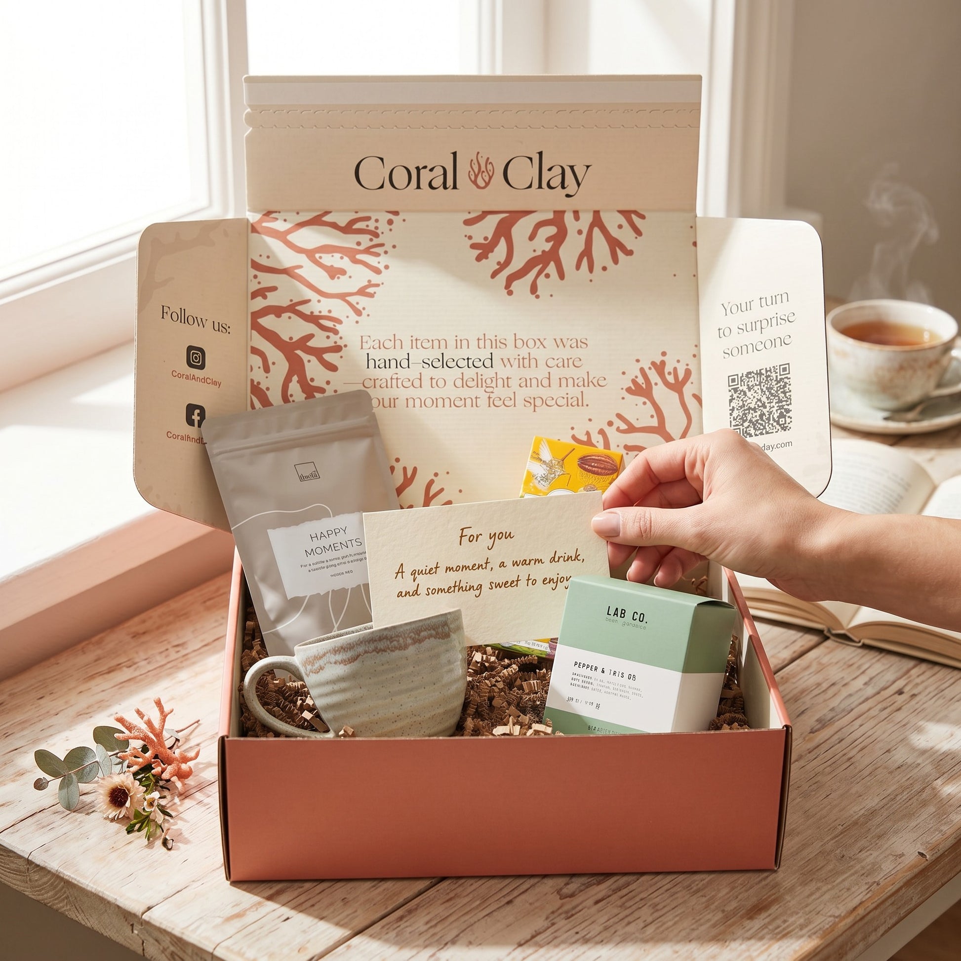 Coral Clay gift box with tea bags and a cup on a wooden table.