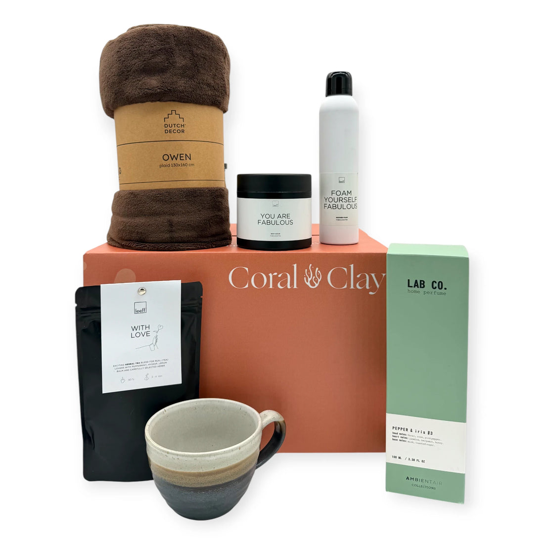 The Coral & Clay Grand Body & Mind Gift Box displayed with all items arranged around the signature terracotta gift box, featuring a brown cozy blanket, artisan ceramic mug, Leeff ‘With Love’ tea, Leeff shower foam and body scrub, and Lab Co. home perfume.
