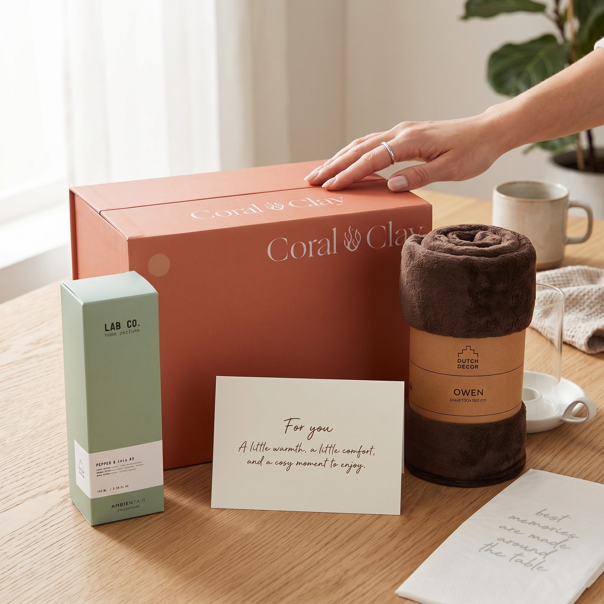 Coral & Clay product with a blanket and card on a wooden surface