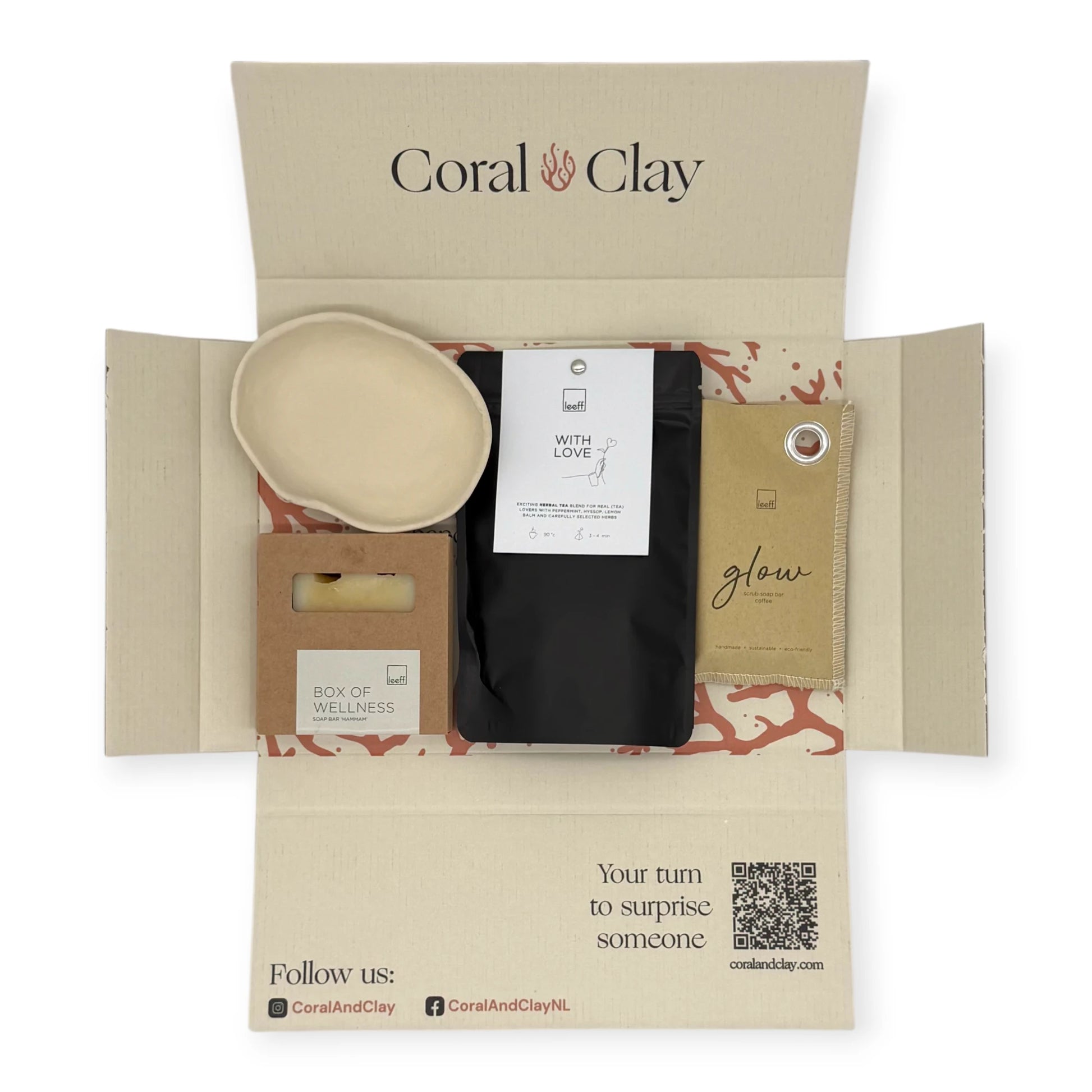 Top-down view of the Coral & Clay Body & Mind Letterbox Gift opened to reveal the Box of Wellness soap bar, With Love herbal tea, Glow sachet, and ceramic dish inside the printed mailer box.