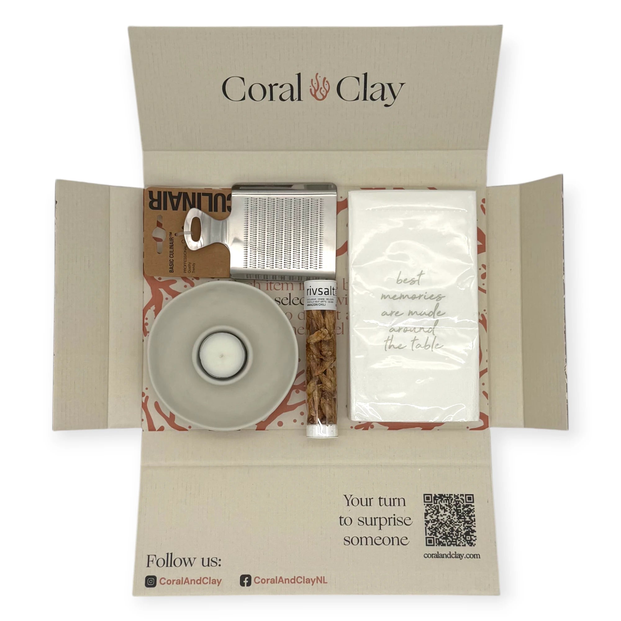 Top-down view of the Candlelight Dinner Letterbox Gift opened flat, showing the ceramic tealight holder, Rivsalt chili tube, stainless-steel grater, and printed dinner napkins arranged inside the Coral & Clay box.