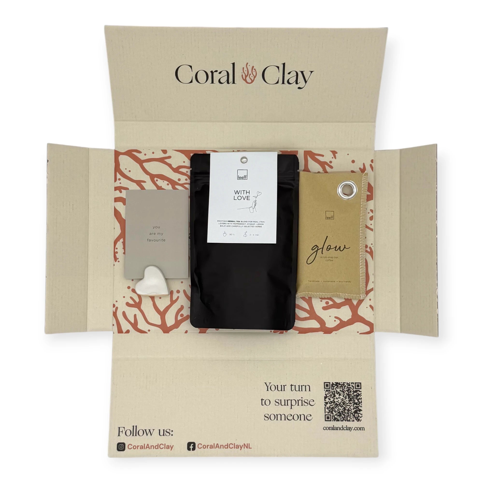 Top-down view of the Coral & Clay With Love Letterbox Gift opened to show Leeff herbal tea, Glow sachet, and message card with ceramic heart stand inside the printed mailer box.
