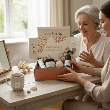 Coral & Clay Get Well Soon gift box on a wooden table, featuring luxury self-care items like lotion, bath salts, and a decorative ball. A steaming mug, seashells, and coral accents add a calming touch, with soft natural light coming through a window in the background.