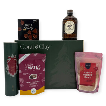 Christmas Scents Signature Gift displayed with Coral & Clay Christmas box and winter treats: glühwein mix, festive cookie mix, speculoos syrup, Christmas tree diffuser, and milk-chocolate Party Cacao shapes.”