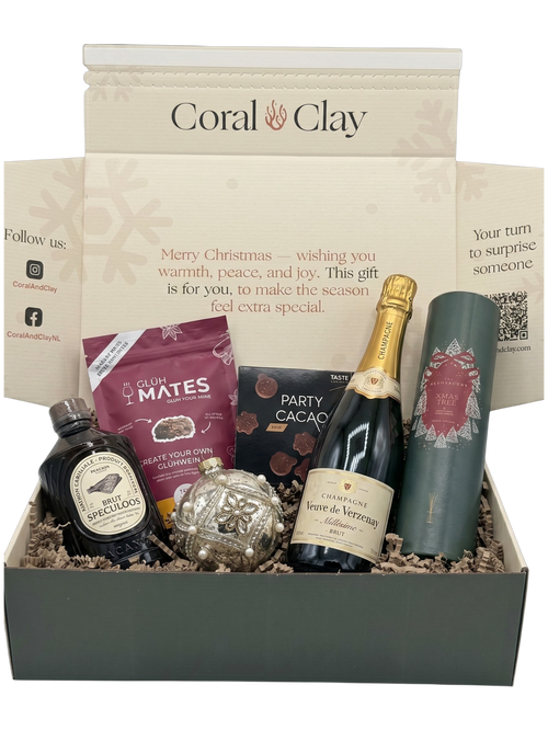 Cadeaubox met diverse items, waaronder een fles wijn, chocolade en een fles gin, met ‘Coral & Clay’-logo.
