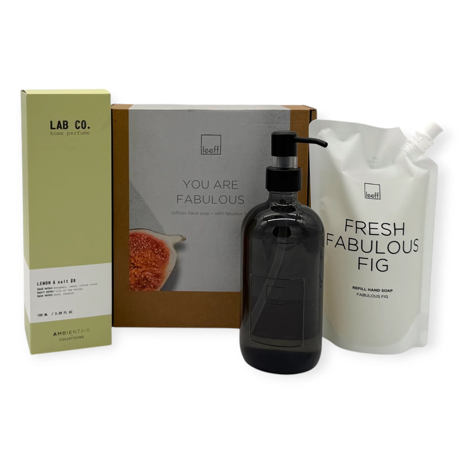 Signature Hands & Home gift set components displayed on a white background, featuring Leeff Fresh Fabulous Fig hand soap refill pouch, black glass soap dispenser, Lab Co Lemon & Salt home perfume, and You Are Fabulous gift box.