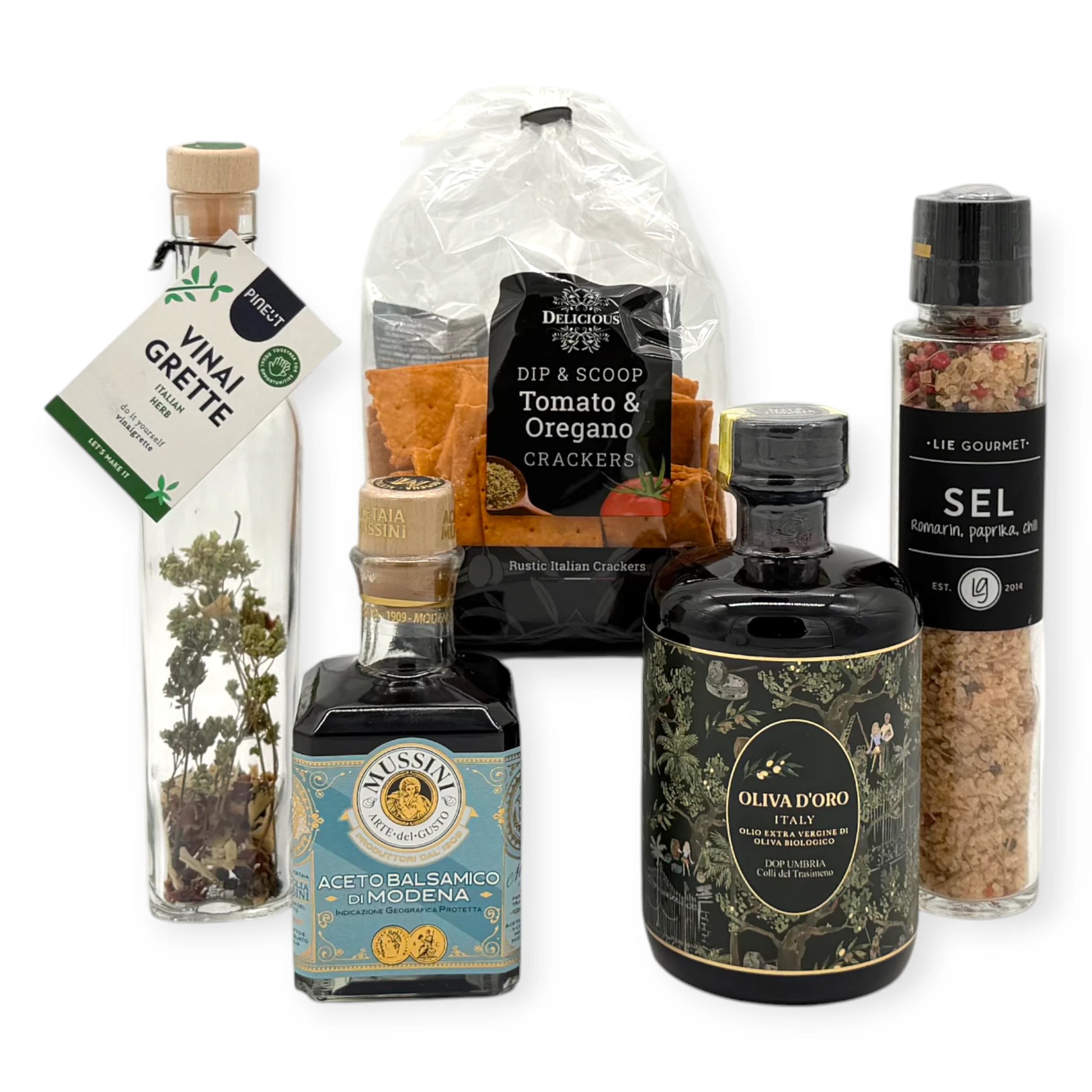 Italian antipasti selection including tomato and oregano crackers, herbed vinaigrette bottle, Modena balsamic vinegar, gourmet salt grinder, and premium Italian extra-virgin olive oil.
