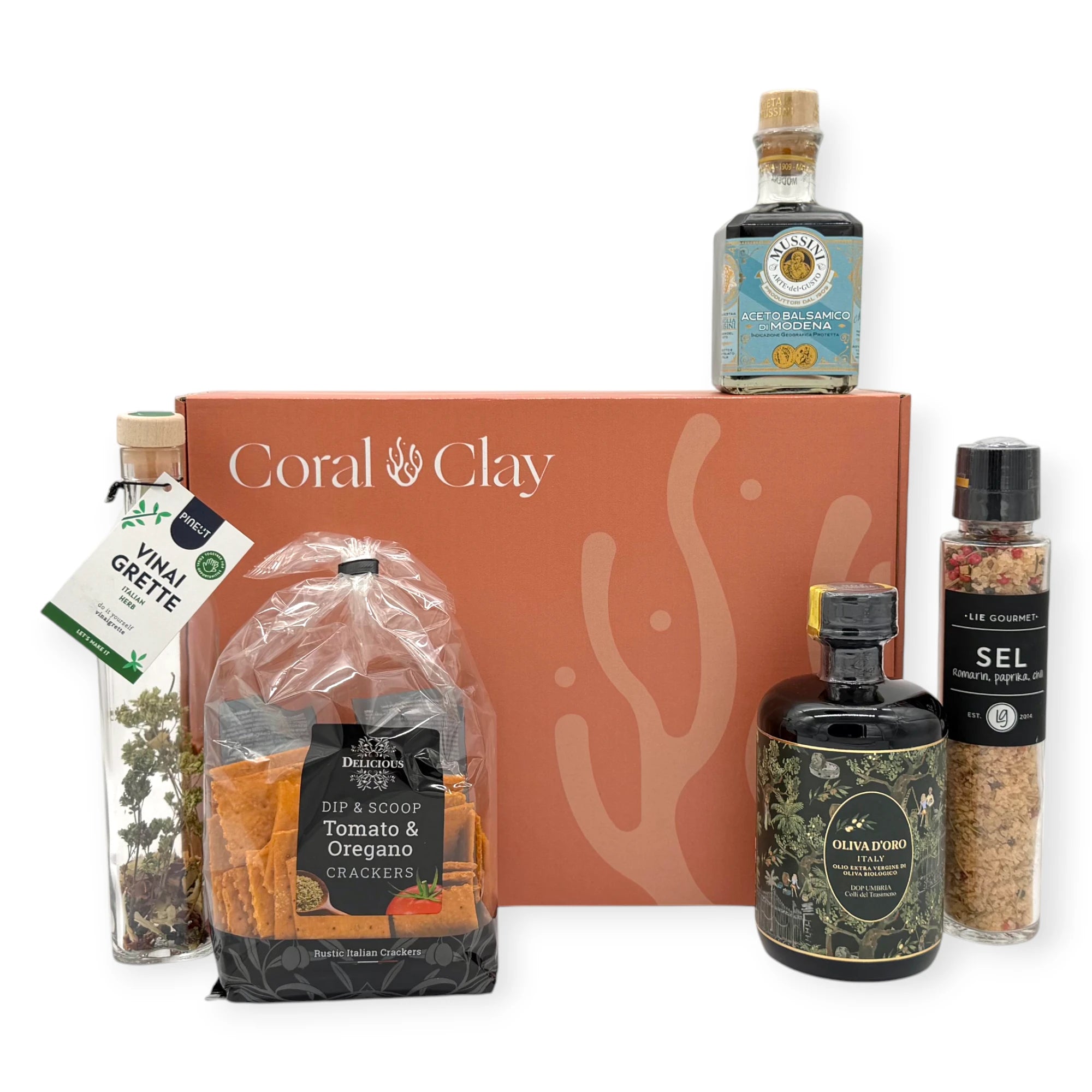 Coral & Clay Signature box surrounded by Italian antipasti items including Italian vinegar, herbed vinaigrette, tomato and oregano crackers, and gourmet salt.