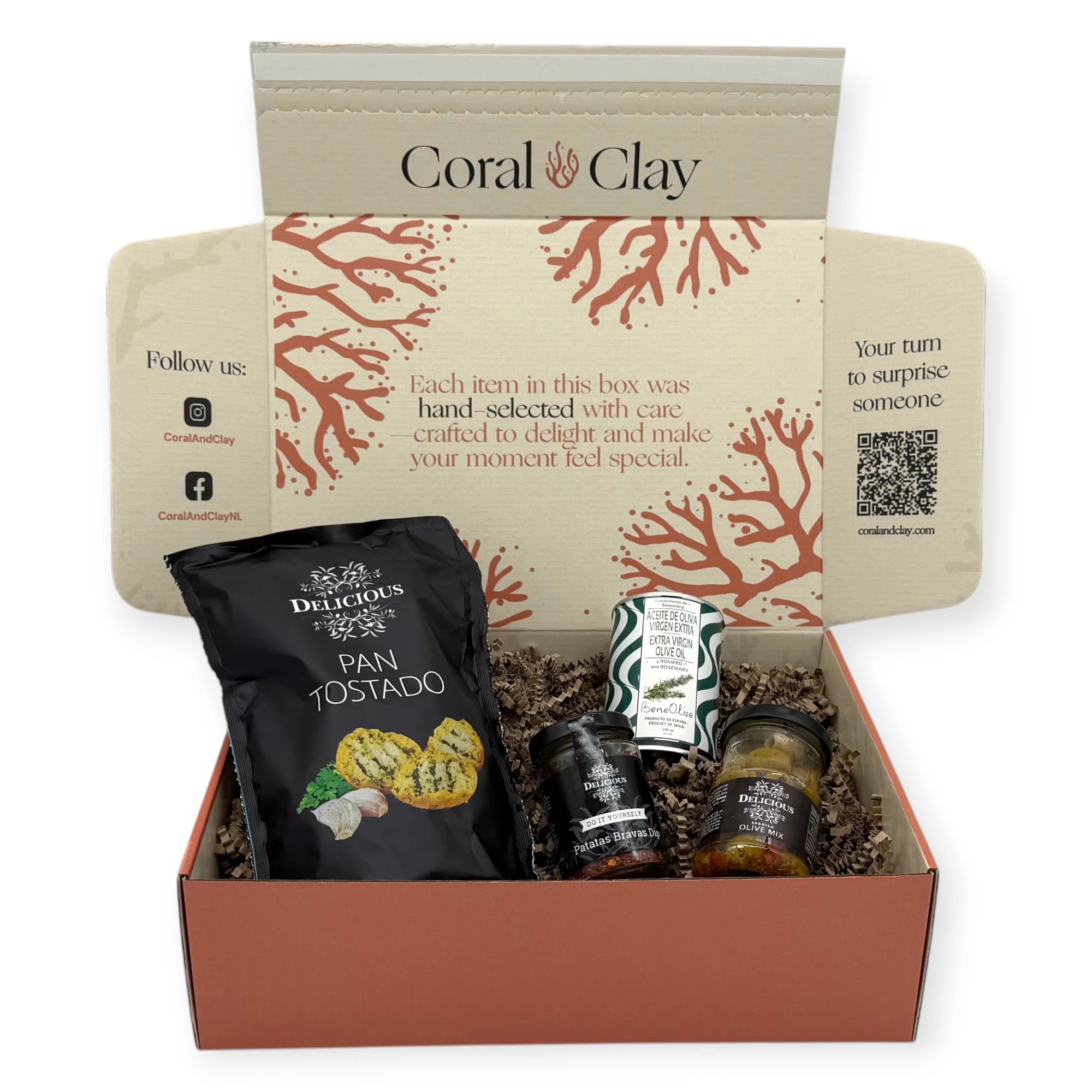 Taste of Spain gift box opened and viewed from above, showing Pan Tostado crispbread, BeneOlive rosemary olive oil, Patatas Bravas dip mix, and seasoned olive mix nestled in kraft filler inside the Coral & Clay printed interior.